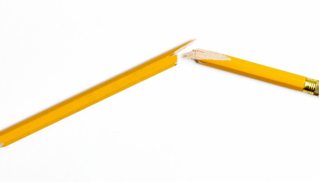 Broken yellow wooden pencil photographed on white background