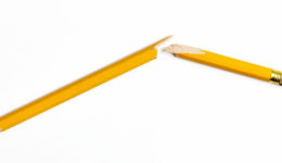 Broken yellow wooden pencil photographed on white background